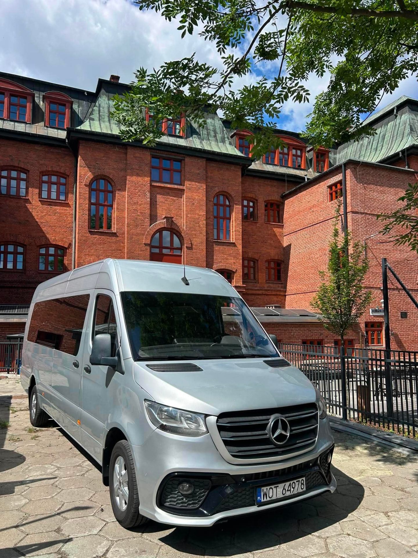 Srebrny Mercedes-Benz Sprinter przed zabytkową kamienicą — transport grupowy
