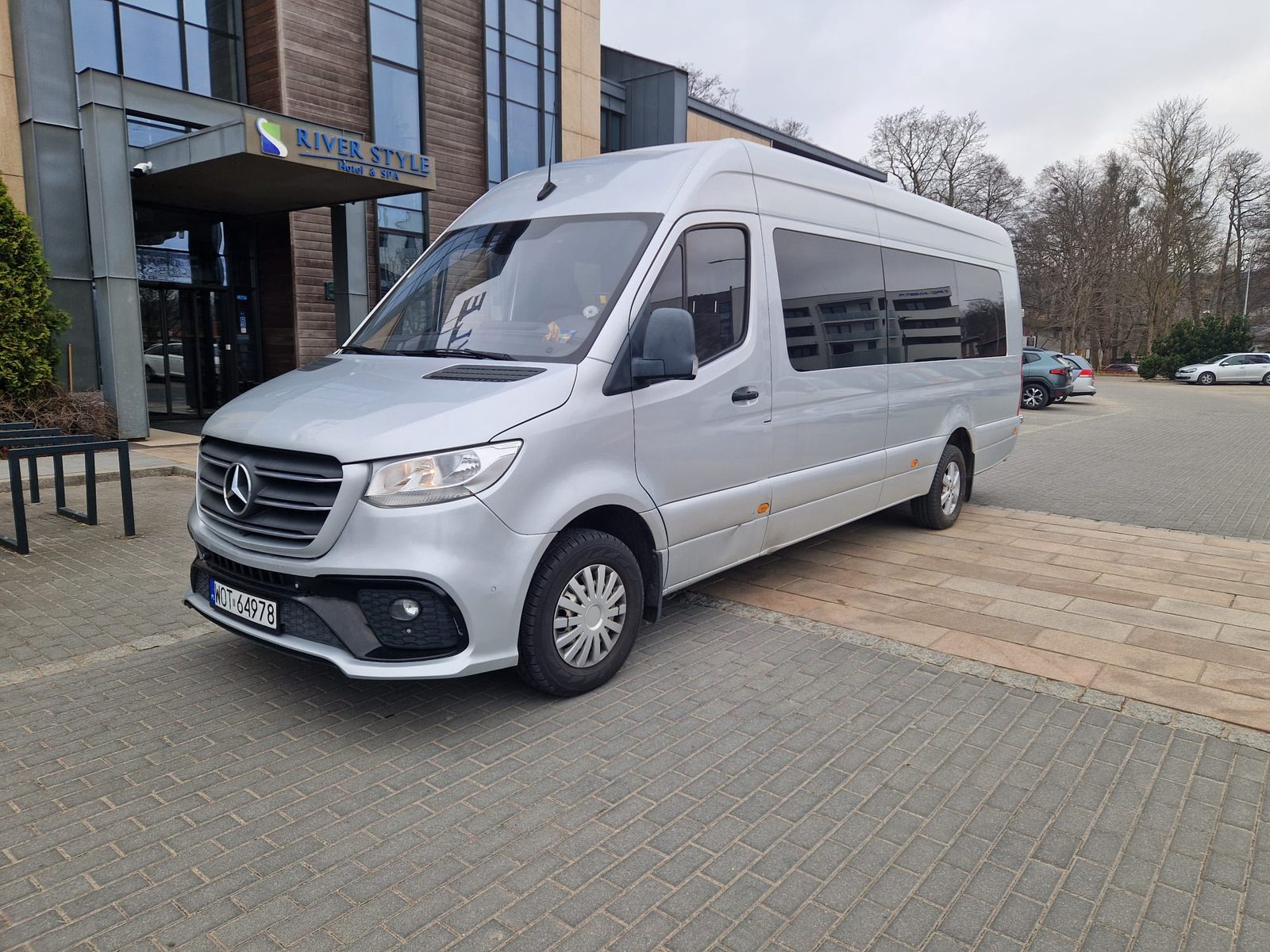 Srebrny Mercedes-Benz Sprinter przed hotelem River Style Hotel & SPA